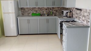 Eine Küche mit grauen Schränken, einem weißen Kühlschrank, einer Mikrowelle und einem Herd.
