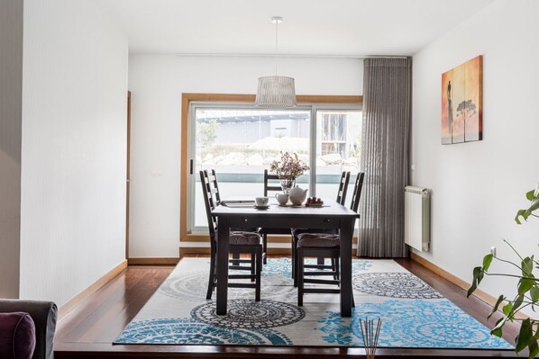 A dining area with a table, chairs, and a view through a large window.