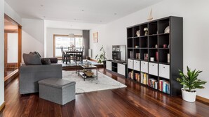 Una sala de estar moderna con un sofá gris, una mesa de centro, una estantería y un comedor al fondo.
