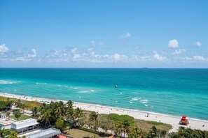 A beach with clear turquoise water, a lifeguard tower, and palm trees.