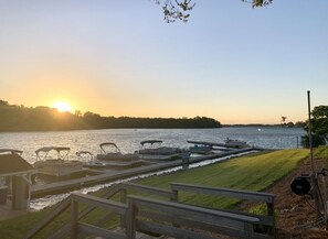 Ein Yachthafen mit vertäuten Booten, einer Holzpromenade und einem Sonnenuntergang im Hintergrund.
