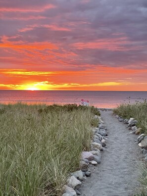 A pathway leading to a beach with a sunset view.