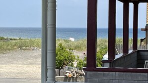 Een veranda met uitzicht op de oceaan, een stoel en een stenen muur.