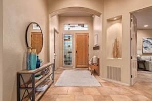 A hallway with a wooden bench, a mirror, and a vase on a console table.