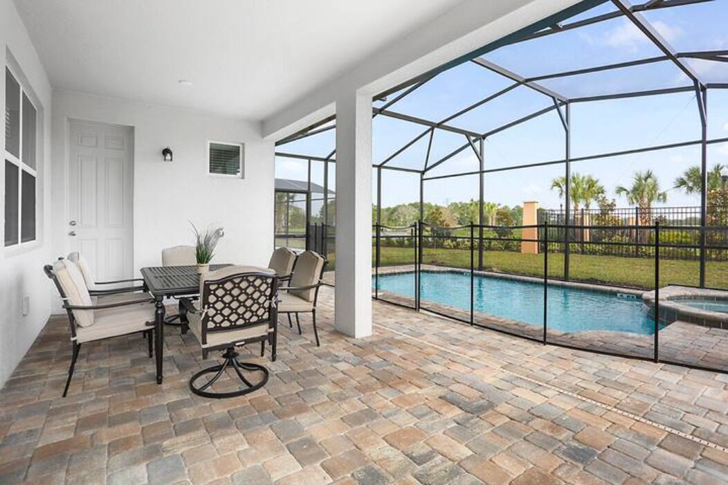 A covered patio with a pool, a dining table with chairs, and a view of the outdoors.