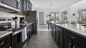 Una cocina moderna con armarios oscuros, electrodomésticos de acero inoxidable y una isla grande.