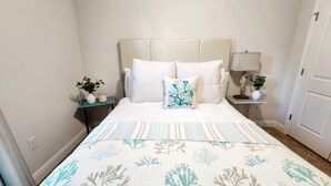 Een keurig opgemaakt slaapkamer met een bed, twee nachtkastjes en een bedbank.