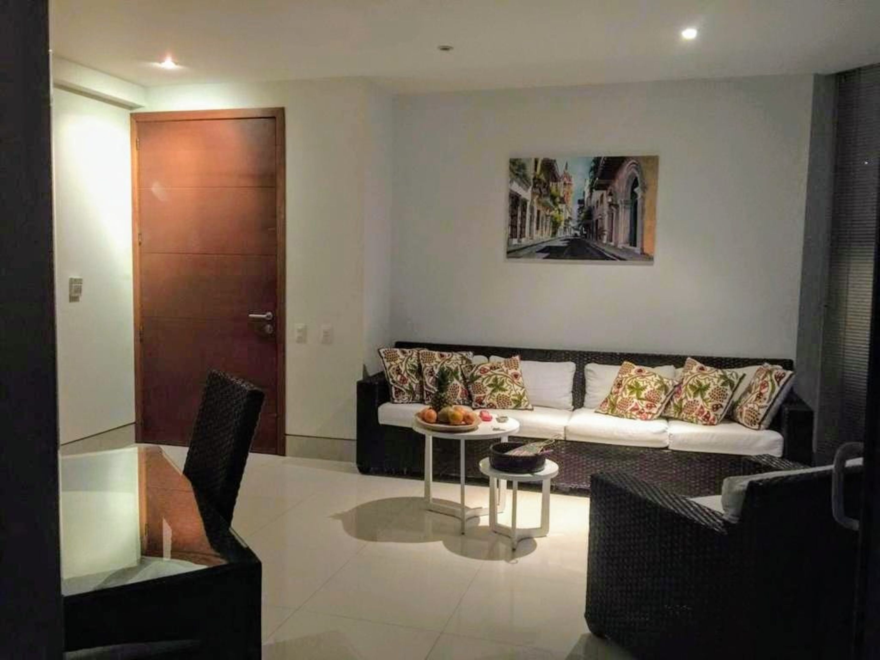 Un salon moderne avec un canapé, deux fauteuils, une table basse et un tableau accroché au mur.