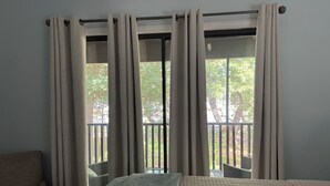 Una habitación con cama, una silla y una ventana con cortinas.