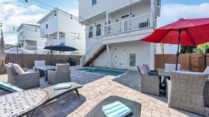 A backyard with a swimming pool, outdoor furniture, and a wooden deck.