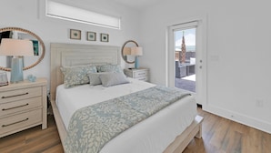 Un dormitorio con cama, mesitas de noche, cómoda y ventana.