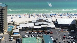 Strandblick mit Hotel, klarem Himmel und einem Parasegel im Hintergrund.