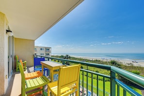 A balcony with a view of the beach, featuring a table and chairs. - Oceanfront Beach Condo w/ Stunning Views! (North Myrtle Beach)