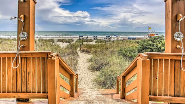 A wooden pathway leading to beach huts with a view of the beach and ocean. - Oceanfront Beach Condo w/ Stunning Views! (North Myrtle Beach)