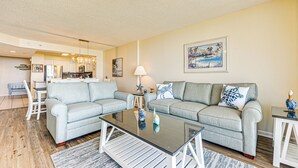 A living room with two grey sofas, a glass coffee table, and a dining area with a white table and chairs. - Oceanfront Beach Condo w/ Stunning Views! (North Myrtle Beach)