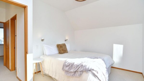 A bedroom with a bed, a bedside table, and a wall-mounted light fixture.