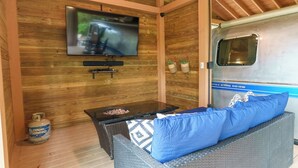 Un espacio de sala acogedor con televisor, sofá de mimbre y una mesita.