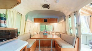 Interior compacto de una caravana con kitchenette, comedor y zona de estar.