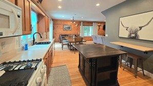 Una cucina moderna con piano cottura a gas, pensili in legno e un'area pranzo con tavolo e sedie.