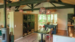 A rustic kitchen with a large island, wooden beams, and hanging glass chandeliers.