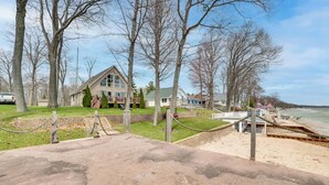 A beachfront property with a large house, a dock, and a sandy beach. - Waterfront Lake Huron Home - Private Beach! (Tawas City)
