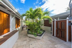 A courtyard with a central planter, white walls, and a wooden gate. - La Villa Hibiscus (Orient Bay)