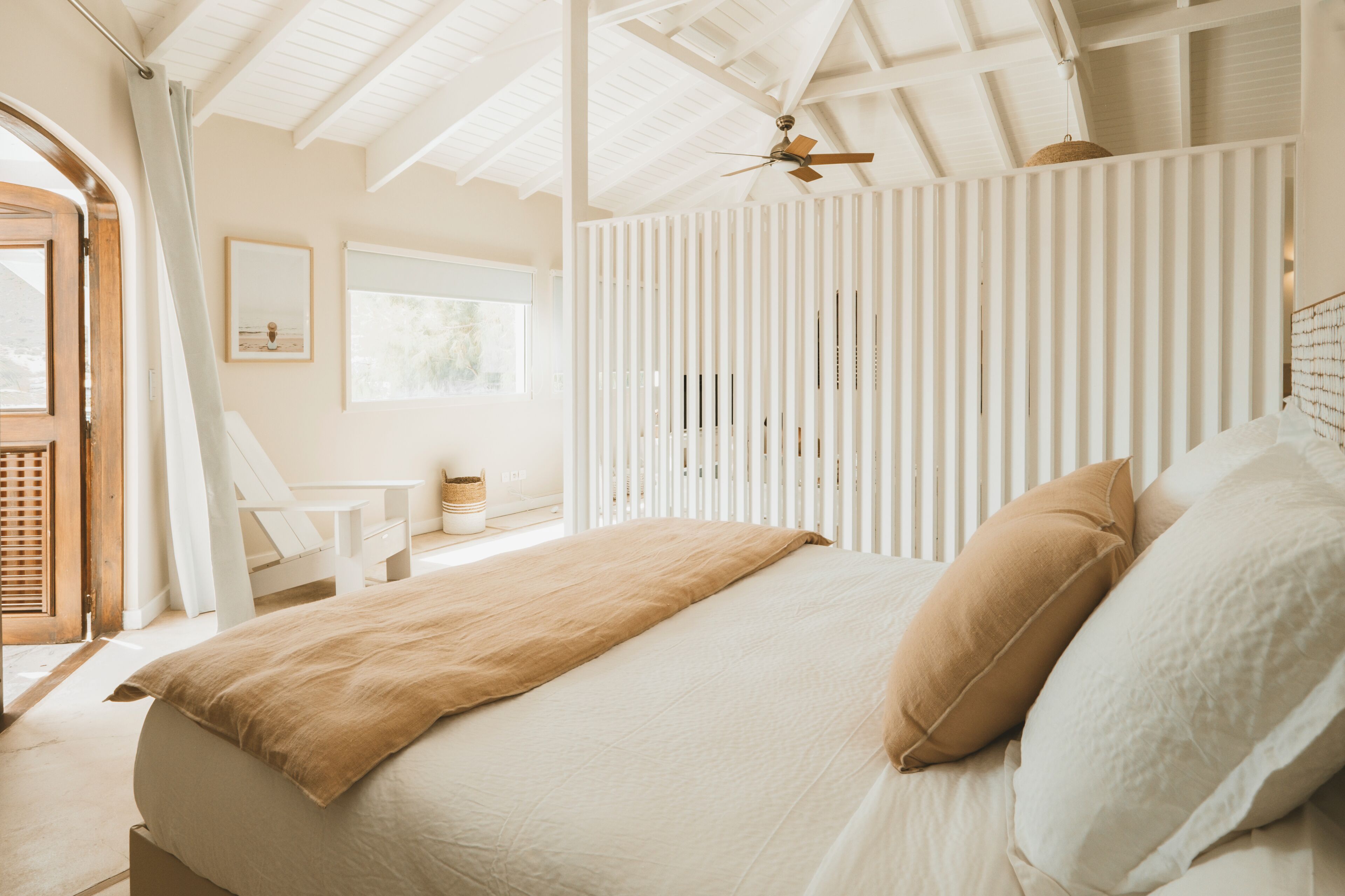 Une chambre à coucher avec un lit, un ventilateur de plafond, une fenêtre et une porte.