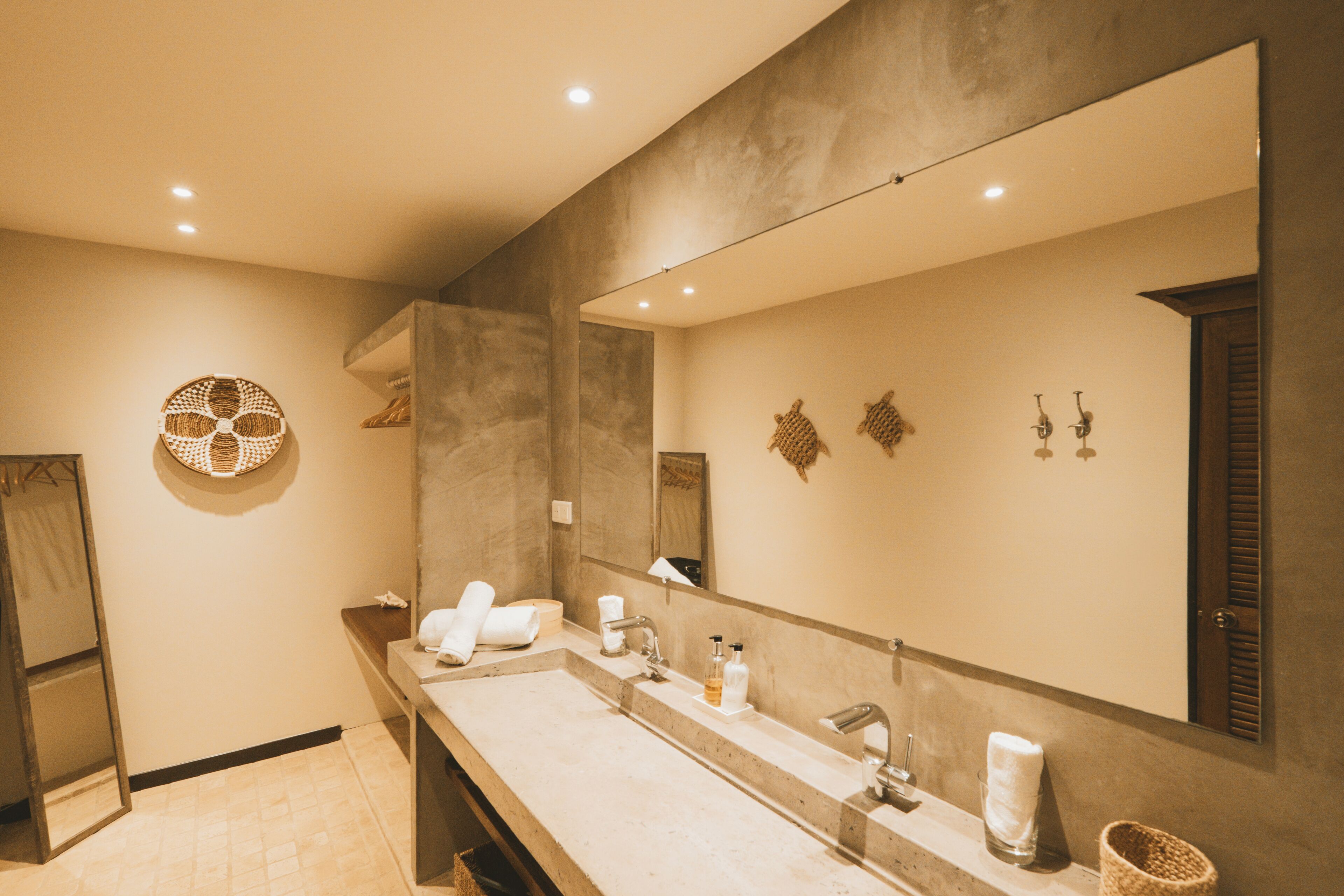 Un baño moderno con un espejo grande, dos lavamanos y un perchero para toallas.