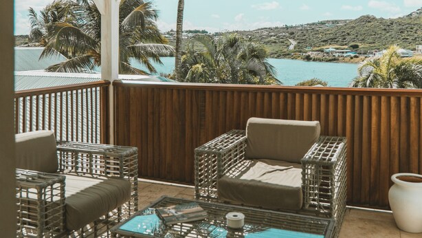 Un espacio de estar techado al aire libre con muebles de mimbre y vistas al mar.