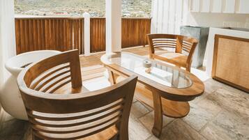 A wooden dining table with chairs, a glass top, and a view of a mountainous landscape.