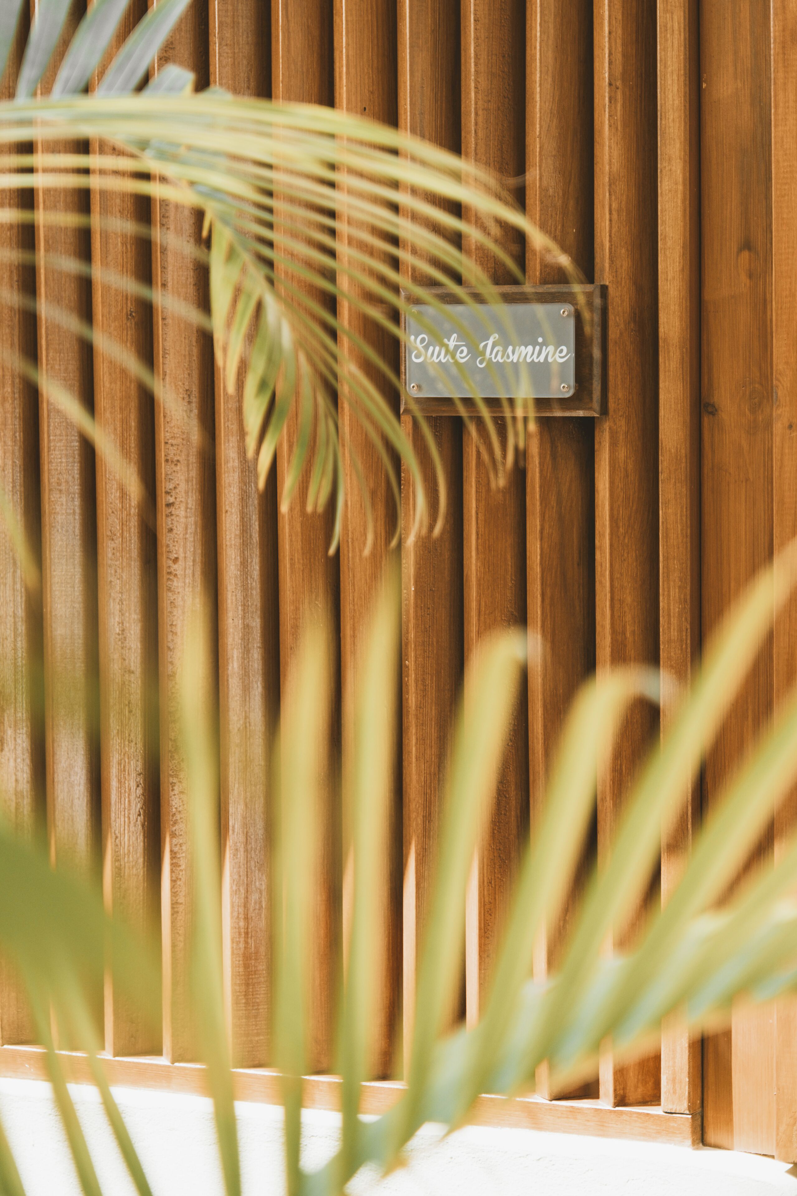 A wooden wall with a sign that reads "Suite Jasmine."