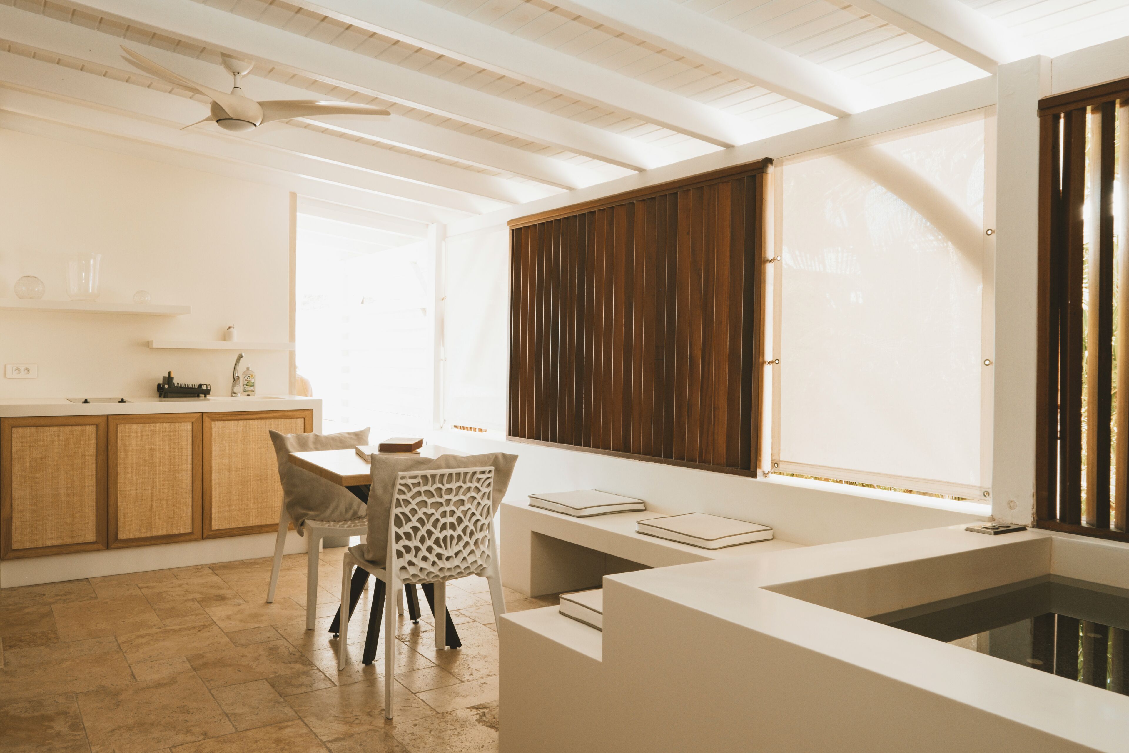 Una cocina moderna con comedor, un banco integrado y un amplio ventanal con persianas.