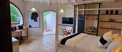 Un dormitorio con cama, televisión, armario y escritorio con silla.