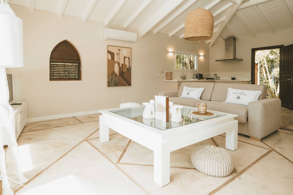 A modern living room with a glass coffee table, a sofa, and a dining area.