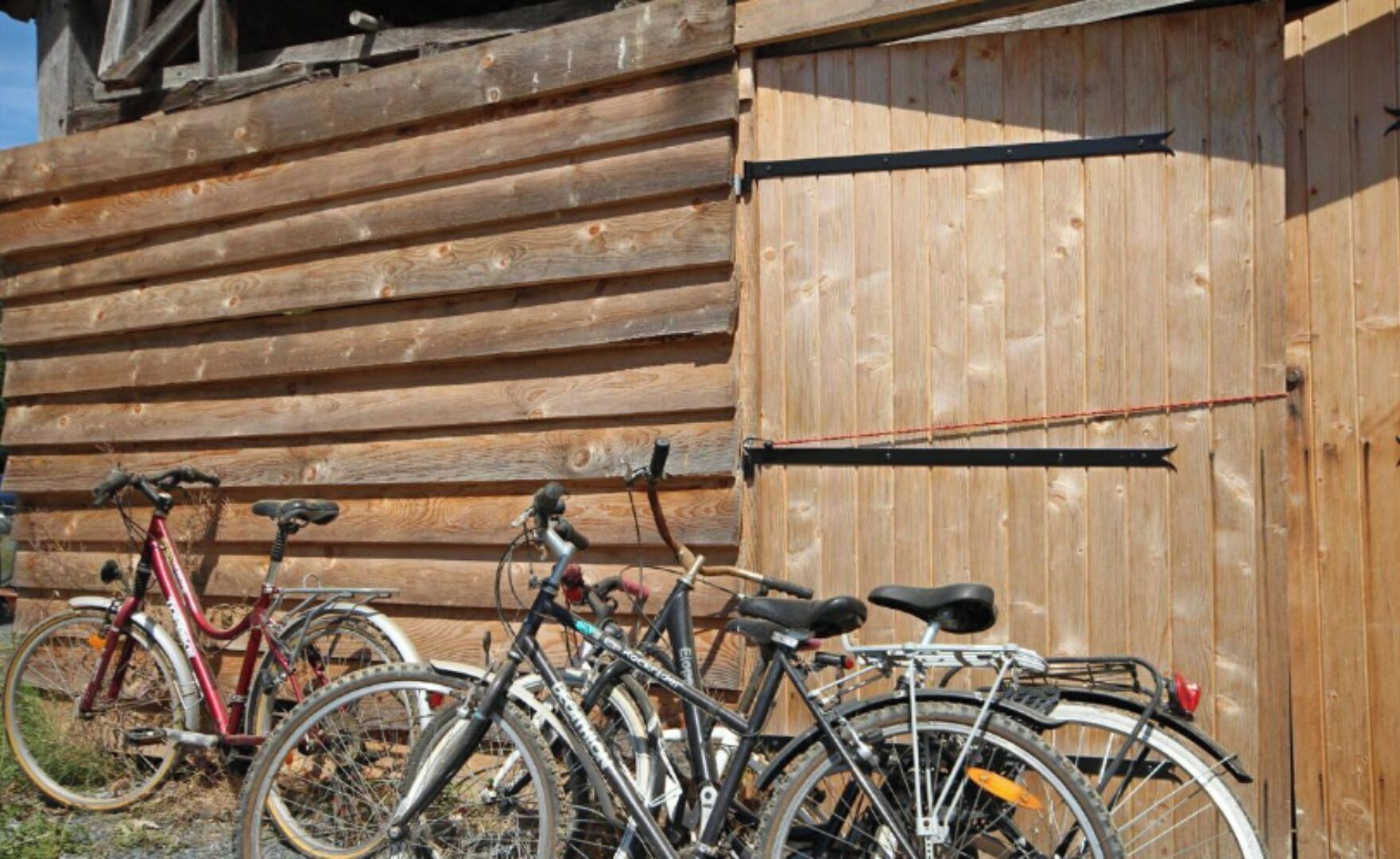 Fietsen staan voor een houten gebouw met een metalen hek.