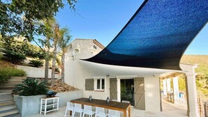 Un patio al aire libre con una mesa y sillas, una pérgola y vistas a una ladera.