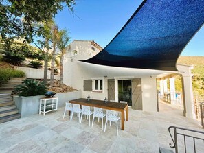 Une terrasse extérieure avec une table et des chaises, une pergola et une vue sur une colline.