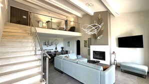 Una sala de estar moderna con escalera, un sofá, una chimenea y un televisor.