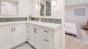 A modern bathroom with a large mirror, a sink, and a shower area. - Upscale Family Home · 5 miles to Disneyland (Fullerton)