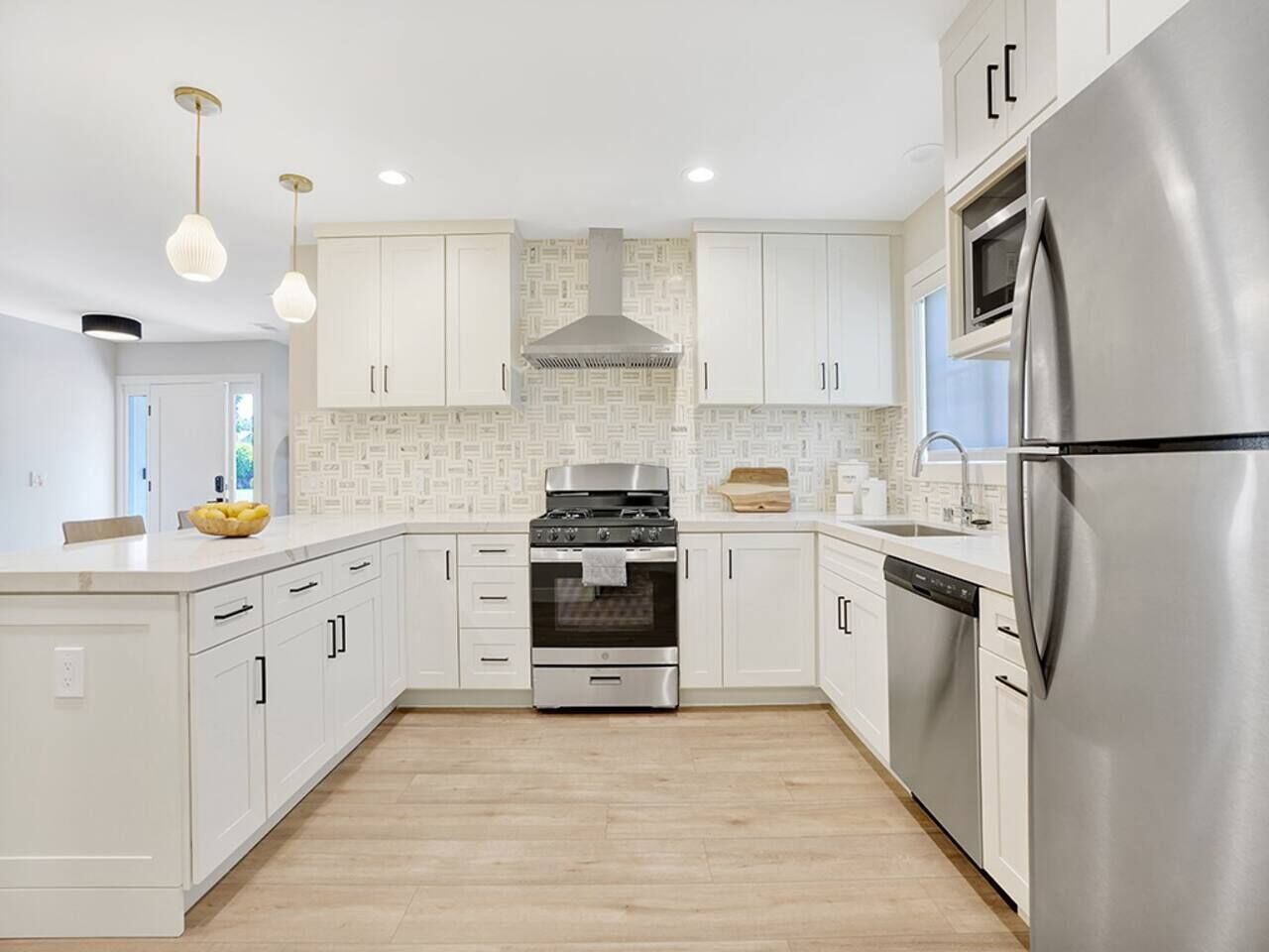 Una cocina moderna con armarios blancos, electrodomésticos de acero inoxidable y una isla central.
