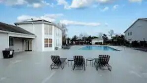 A swimming pool area with lounge chairs and a building in the background. - K4 Gulf Shores Vacation Getaway II (Gulf Shores)