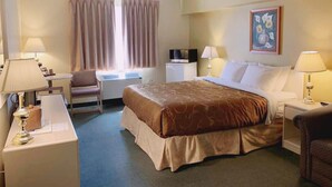 Una habitación de hotel con una cama, dos mesitas de noche, un escritorio, una silla, un televisor y una ventana con cortinas.