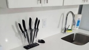 A kitchen with white cabinets, a stainless steel sink, and a stove.