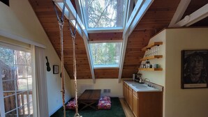Ein gemütliches Schlafzimmer im Dachgeschoss mit Oberlichter, Holzbalken, einer Schaukel und einer Küchenzeile.