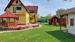 Ein zweistöckiges Haus mit rotem Dach, einem Balkon und einer Holzterrasse.