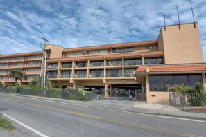Un hotel de varios pisos con techo plano, balcones y un área de estacionamiento.