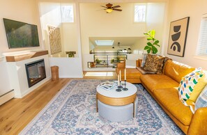 A living room with a fireplace, a sofa, a coffee table, and a large plant.