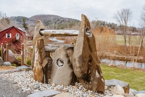 A rustic stone structure with a red barn in the background.