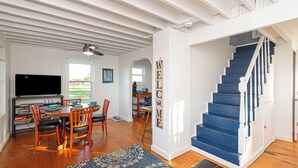 A spacious living area with a wooden dining table, chairs, and a blue staircase.