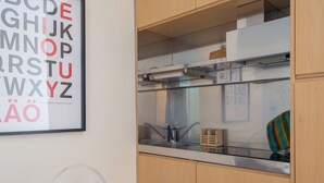 Une cuisine avec un évier en acier inoxydable, des armoires en bois et une affiche illustrant l’alphabet, encadrée, accrochée au mur.